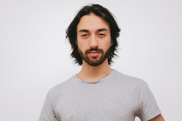 young Latin man with beard and long hair looking at the camera smiling, white background