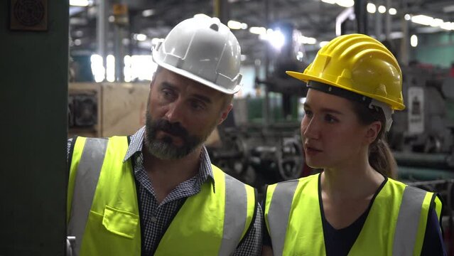 group of Two engineer man and technician worker repair machine discuss with tablet in steel metal manufacturing factory plant industry. team maintenance check quality machine. training explain work