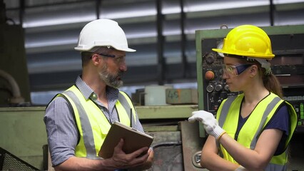 group of Two engineer man and technician worker repair machine discuss with tablet in steel metal manufacturing factory plant industry. team maintenance check quality machine. training explain work