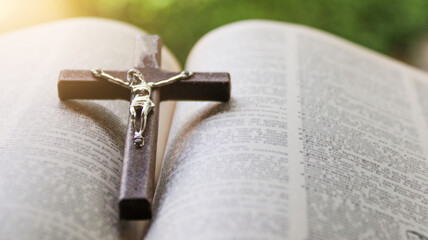 Close up dark brown wooden cross on old books with blur background                                 ...