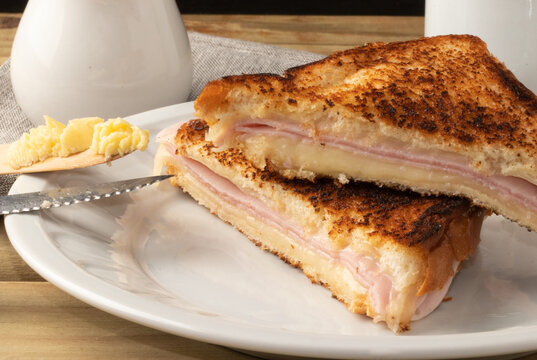 Toasted bread stuffed with ham and cheese on plate.