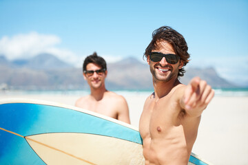 Obraz premium Beach, pointing and man surfing friends outdoor together for summer vacation or holiday trip overseas. Surf, sea or travel with a young male surfer in sunglasses and friend bonding on an ocean coast