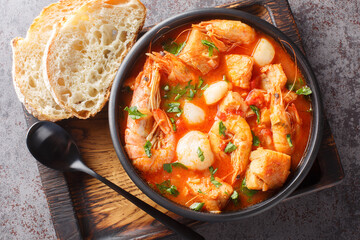 Mediterranean soup of seafood and white fish with shrimp, mussels, scallops, squid close-up in a...