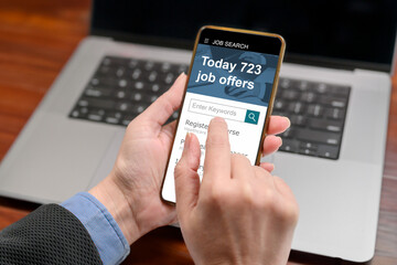 A woman is looking through jobs online using a mobile job search app on her phone. recruitment concept, back view