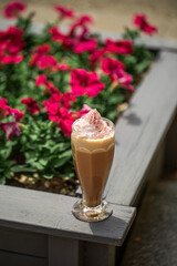 Portion of frappe coffee with cream in the garden with flowers