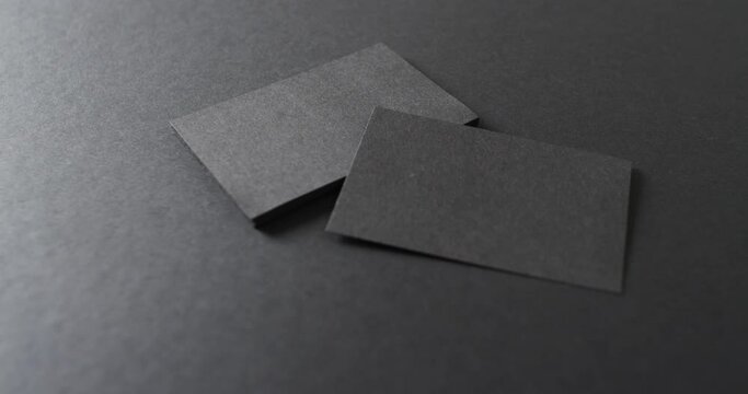 Close up of stack of black business cards on black background, copy space, slow motion