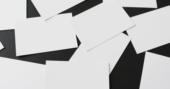Close up of white business cards scattered on black background, copy space, slow motion