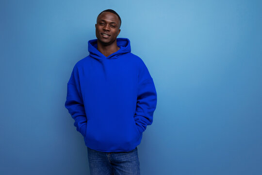 close-up of an african young guy in a blue hoodie on a studio background with copy space