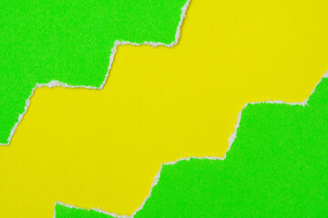 Hole ripped in a green paper on yellow background