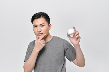 A beautiful smiling man shows the moisturizer that he uses to make his skin smooth and clean from impurities
