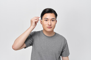 Handsome cheerful man using nourishing serum for his face