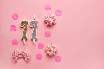 Number 77 on pastel pink background with festive decor. Happy birthday candles. The concept of celebrating a birthday, anniversary, important date, holiday. Copy space. banner