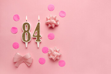 Number 84 on pastel pink background with festive decor. Happy birthday candles. The concept of celebrating a birthday, anniversary, important date, holiday. Copy space. banner