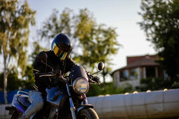 Fototapeta na wymiar motorcyclist in gear and a helmet with a sun visor on a motorcycle in summer