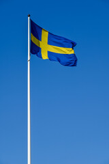 Swedish flag on flag pole and clear blue sky