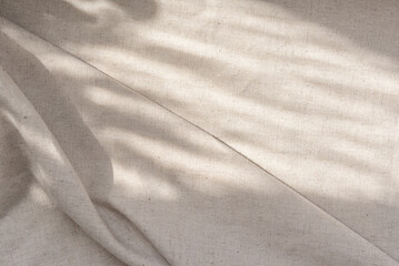 Aesthetic neutral beige linen texture background with soft abstract sunlight shadows and folds