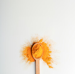 Creative layout made of turmeric powder and wood spoon on a white background. Top view.