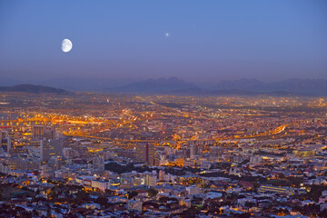 City, Cape Town and night view of building lights and architecture in the industrial urban town of South Africa. Late evening of outdoor scenery of moon or sky over buildings or cityscape structures