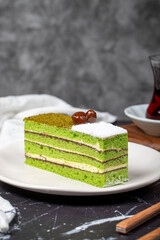 Mini slice colorful green pistachio cake. Delicious cream cake on dark background. Close up