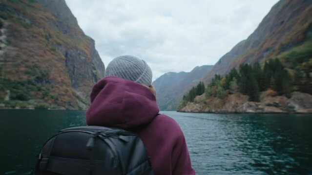 Social media content creator, travel blogger or professional adventure photographer in epic surroundings in Norway. Woman make photos of mountains and fjord. 