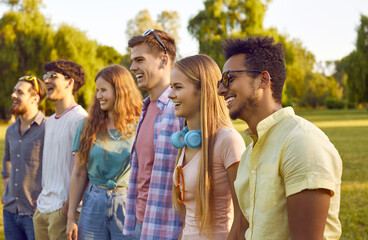 Diverse audience at an outdoor summer festival. Happy people enjoying a concert in nature. Company of young multiethnic male and female friends standing in the park and watching a live open-air show