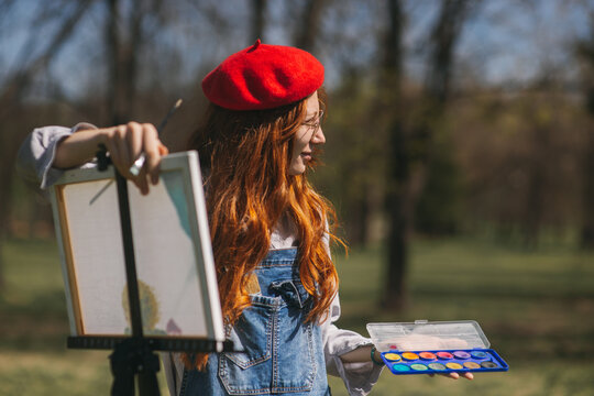 Ginger girl holding a palette and a painting