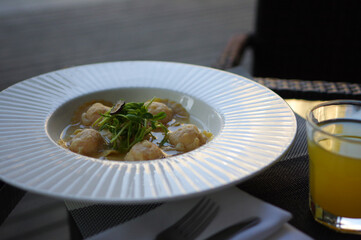 Egg dumplings with black truffle and sprout in white rim bowl