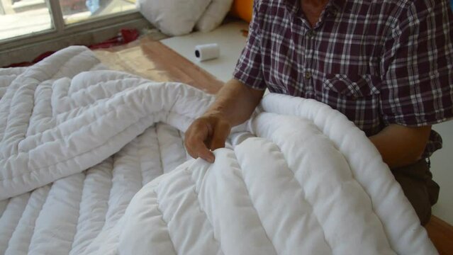 old man sewing a quilt with his hands