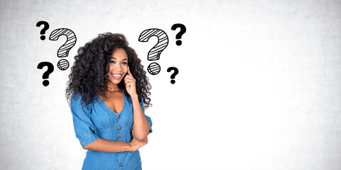 African woman with smiling look, question marks on empty grey wall