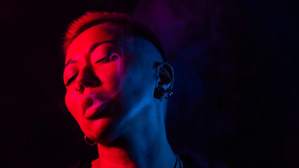 Sensual portrait of asian woman with short haircut smoking in neon light. 