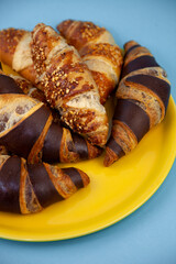 Chocolate croissants or croissant with nut crumbs on a plate. Delicious breakfast on the table. Tasty sweet baking dessert for coffee. Food background. Fresh buttery croissants rolls