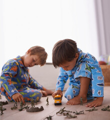 Young boys, playing and toys together in pajamas for fun with miniature action figures, toy car or games. Brothers, sibling children and family bonding in playroom at home for learning or development