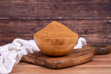 Fototapeta na wymiar Cinnamon powder on wooden background. Powdered dried cinnamon in wooden bowl