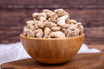 Dried Organic Ginger root on wooden background. Sun-dried ginger root or Dry Adrak in wooden bowl