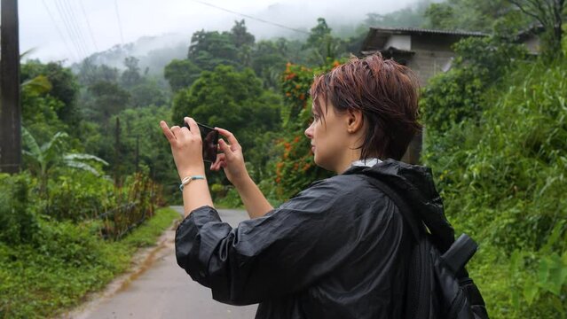 Female tourist taking pictures of local village at Sinharaja Forest Reserve.