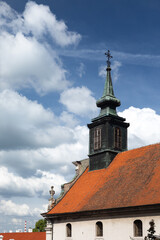 Fototapeta premium Bell tower and roof top of the church against the cloudy sky backdrop.