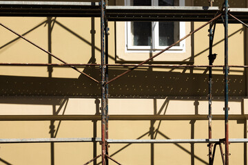 Scaffolding casting a shadow on the wall of the house.