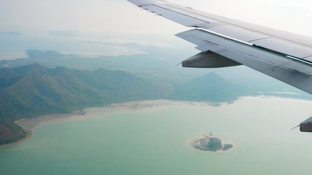 Airplane wing, flight. View of the azure sea, islands and mountains from the porthole. Travel concept