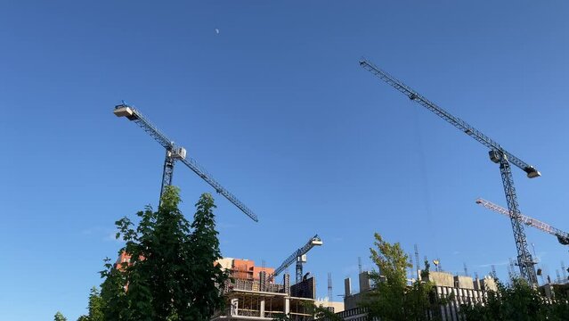 Construction the buildings. Construction process of residential building with cranes and moon on a blue sky. High quality 4k footage