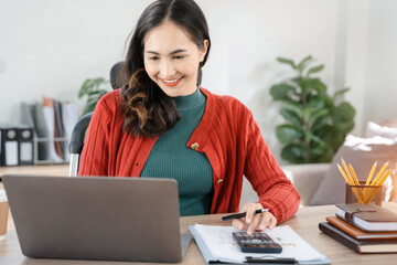 Female businessman working with holding a pen and using a calculator to calculate the numbers of...