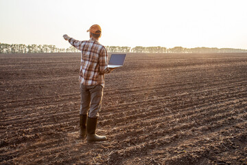  agricultural business concept.  farmer with laptop standing in a field.