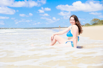 Fototapeta na wymiar ビーチに座るセクシーな水着姿の白人の女の子