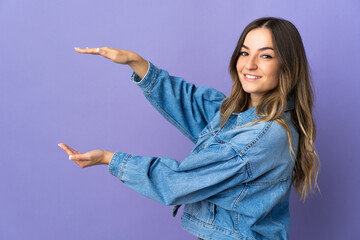 Young Romanian woman isolated on purple background holding copyspace to insert an ad