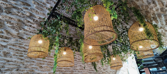Stylish wicker chandelier made of rattan. Several wooden lampshades. Straw lamps. Modern stylish...