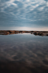 Calm water reflecting the cloudy sky at the beach