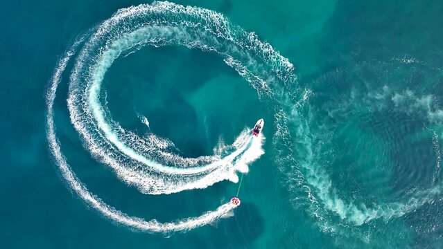 Tubing boat with people moving behind the boat on the water. Aerial view of motor speed boat pulls inflatable rubber raft with people. Summer vacation shot