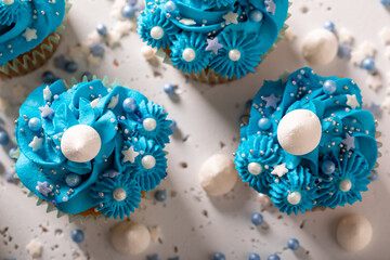 Homemade and delicious cupcakes with sprinkles and blue cream.
