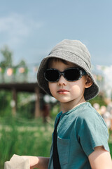 a boy in a gray panama hat looks at the camera on the street. summer walk. children's day. outdoor recreation