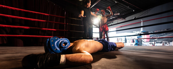 Boxing referee intervene, halting the fight to check fallen competitor after knock out. Referee pauses the action for boxer fighter's safety after KO with winner posing in background. Spur