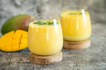 Fotobehang Fresh mango lassi in glasses on grey background with copy space. © Souvik